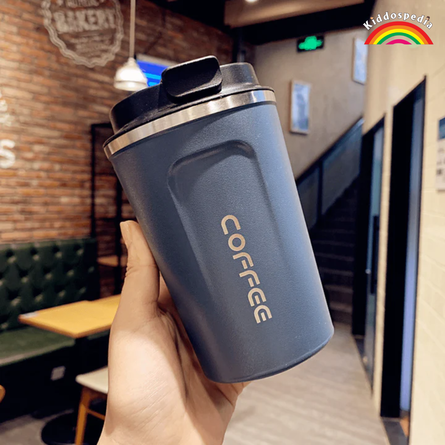 Hand holding a blue coffee tumbler with 'COFFEE' text in a casual setting.