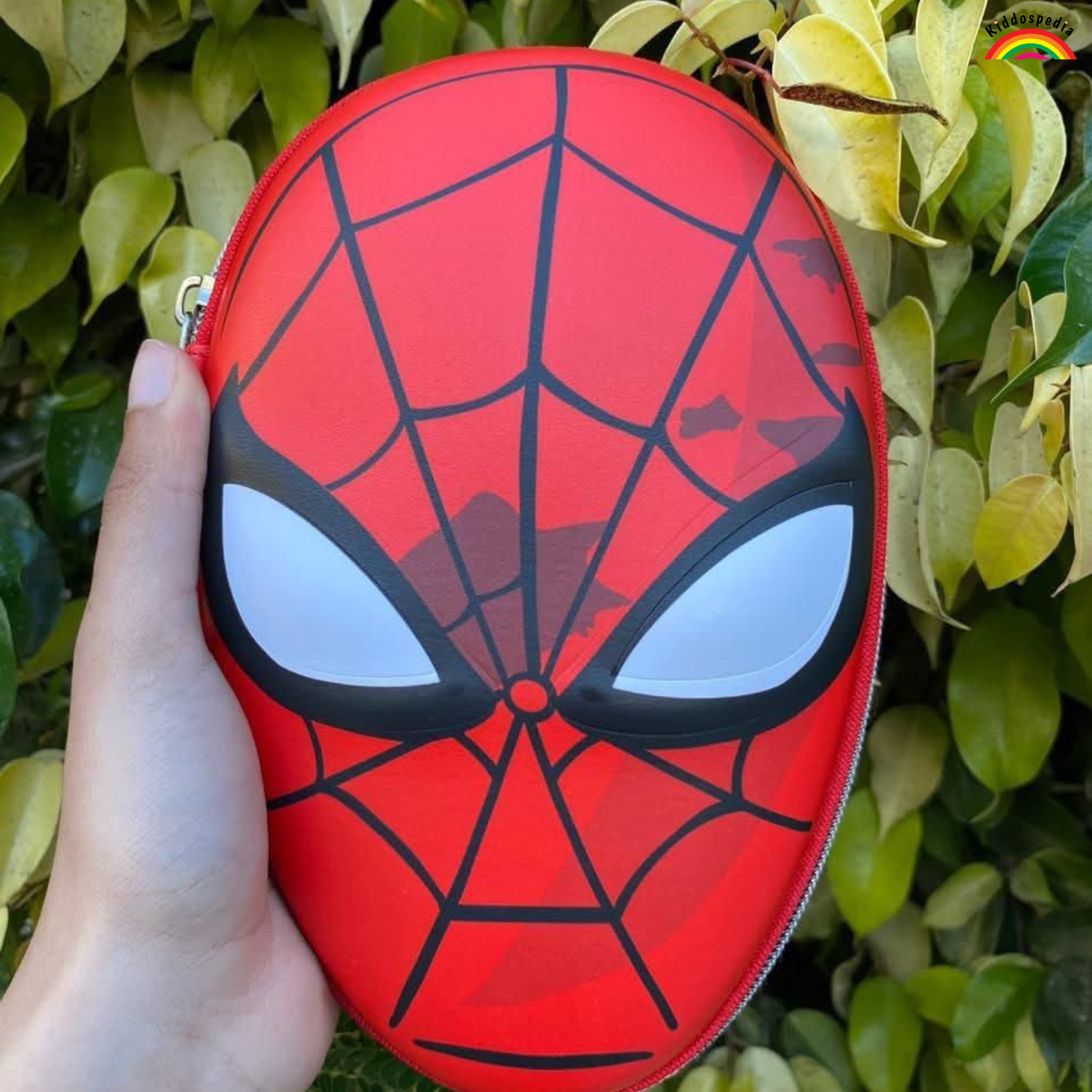 Red Spider-Man face pouch held by a hand with green leaves in the background