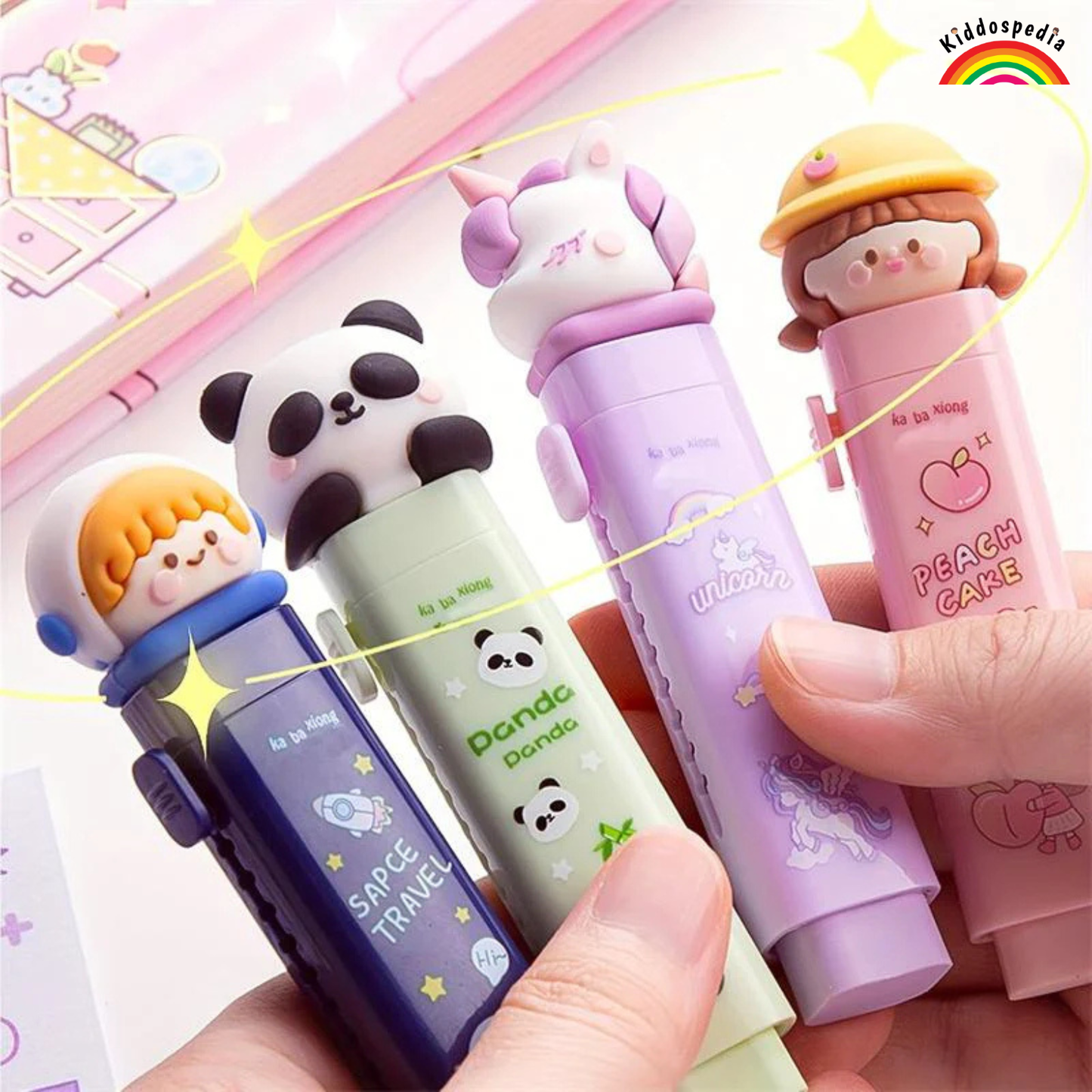 Four colorful pens with cartoon character designs held by a hand against a bright background.
